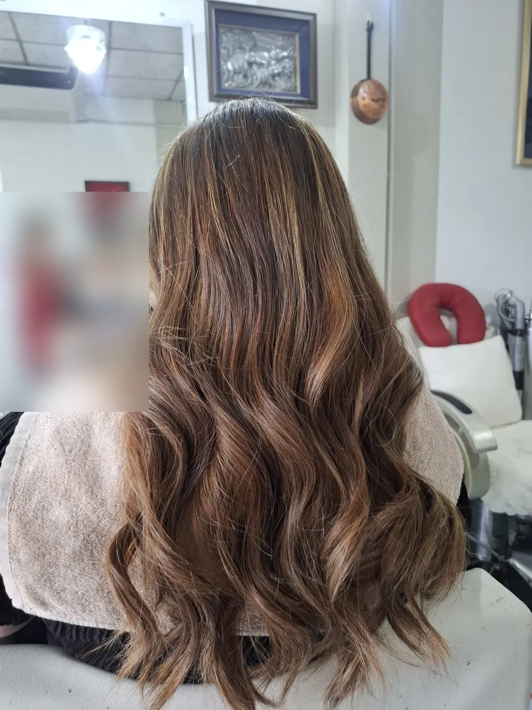Long brown hair with lighter caramel lengths in loose curls, from behind